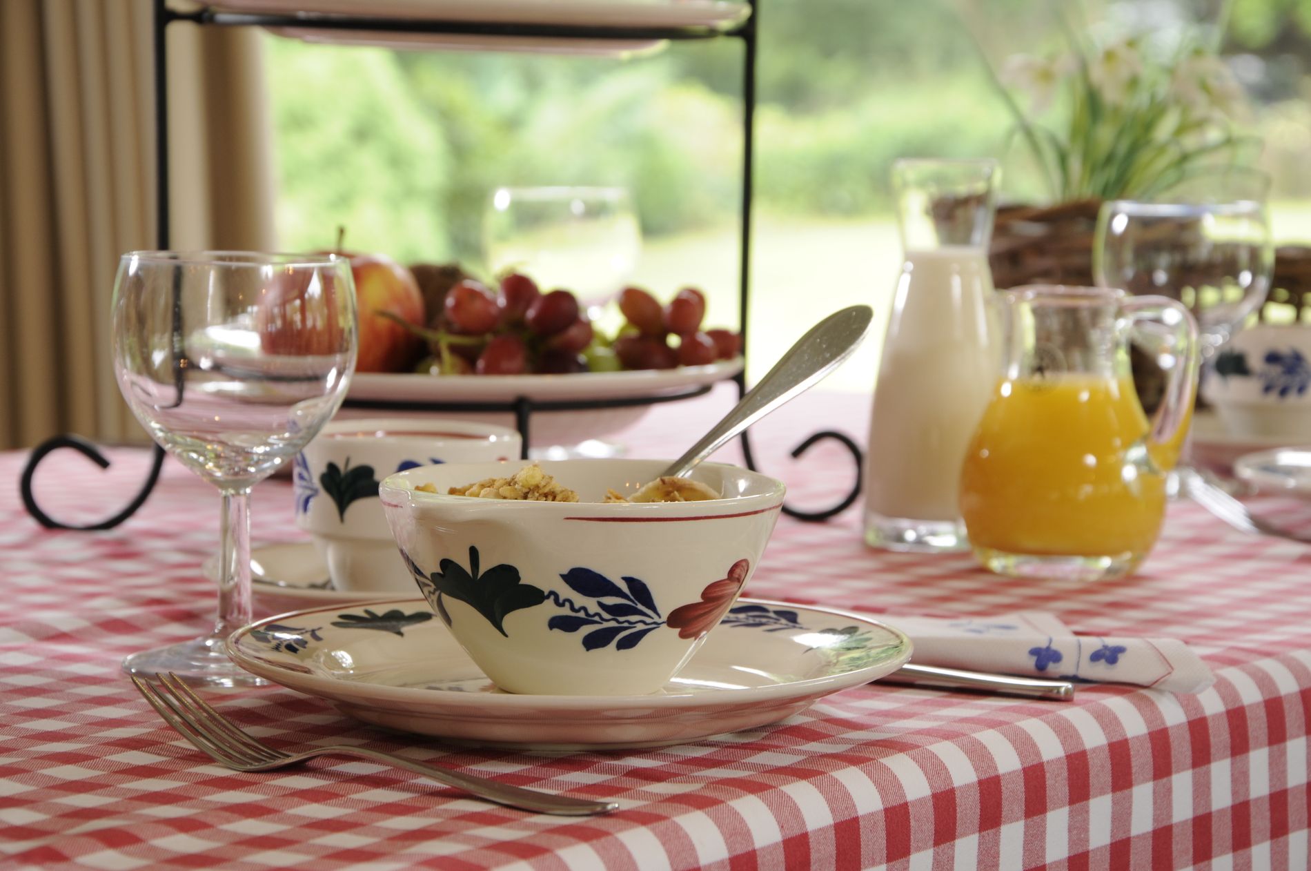 Tafel gedekt met Brabants bont tafelkleed en servies, met een fruitschaal en karaf met jus d'orange en melk.