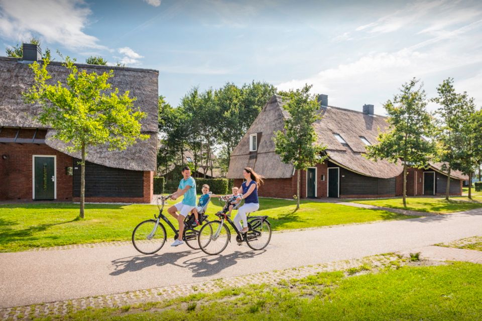 Vader en moeder fietsen met twee kinderen over een vakantiepark in Drenthe.