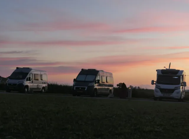 Drie campers op een kampeerveld tijdens de ondergaande zon op Camperplaats en Jachthaven De Appelhof vlakbij Wommels.