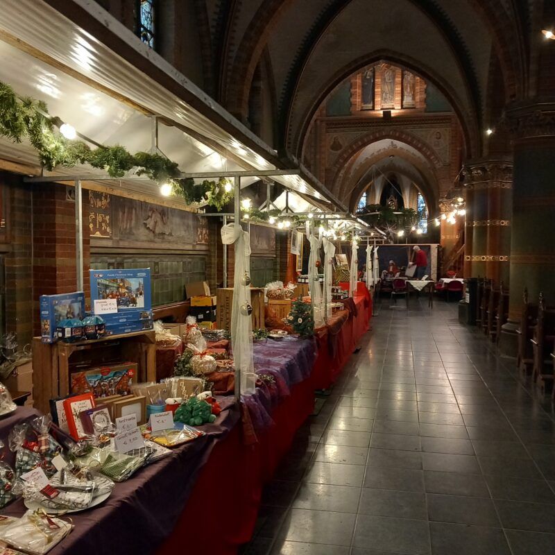 Overdekte kerstmarkt in de Sint-Franciscuskerk in Oudewater, Groene Hart, met sfeervol verlichte marktkramen, kerstversiering en cadeauartikelen onder de hoge gewelven van de historische kerk.