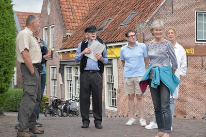 Historische dorpswandeling met gids in Linschoten, gemeente Montfoort, Groene Hart. Groep bezoekers luistert naar een gids in het dorp, omringd door karakteristieke historische panden tijdens een culturele stadswandeling.