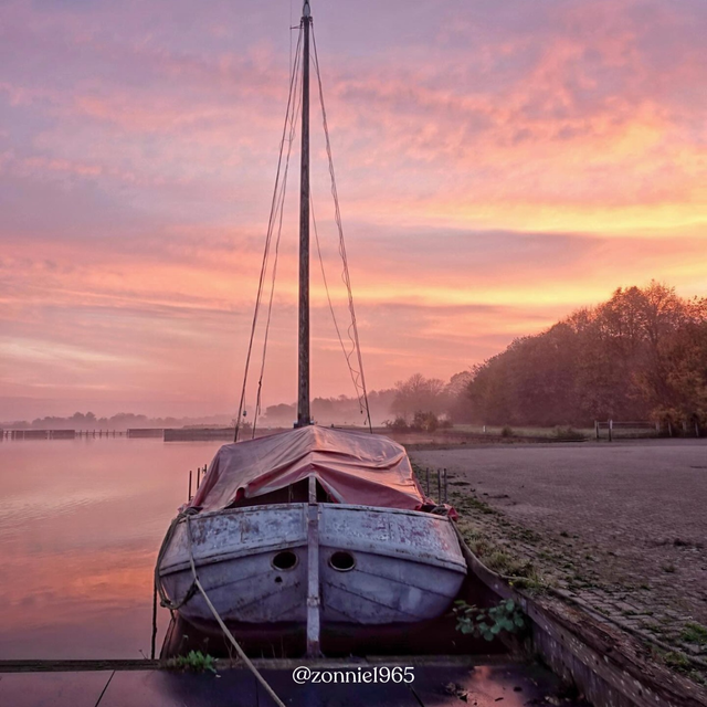 Een foto van een boot in Twiske-Waterland met een roze lucht