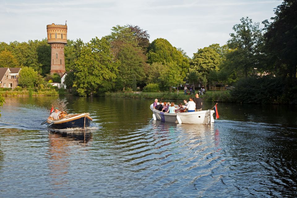 Recreatieve boottocht op de Singel in Woerden, Groene Hart. Sloepen en kleine motorboot varen over het water langs de Watertoren Woerden, omgeven door groen stadslandschap tijdens een zomerse dag.