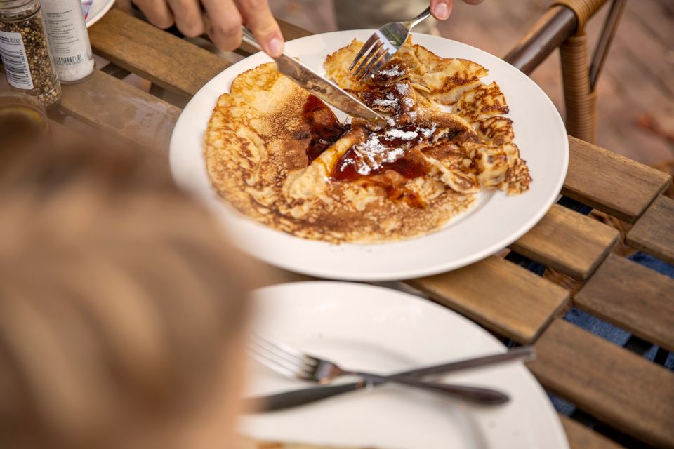 Een pannenkoek met stroop die gesneden wordt.