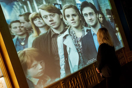 Vrouw staat voor scherm waarop Harry Potter wordt afgespeeld