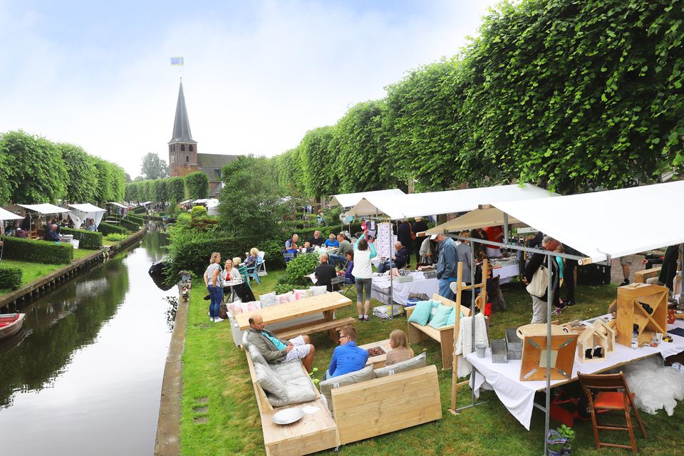 bezoekers overtuinfair ijlst 
mensen op een bank naast de gracht en de kraampjes