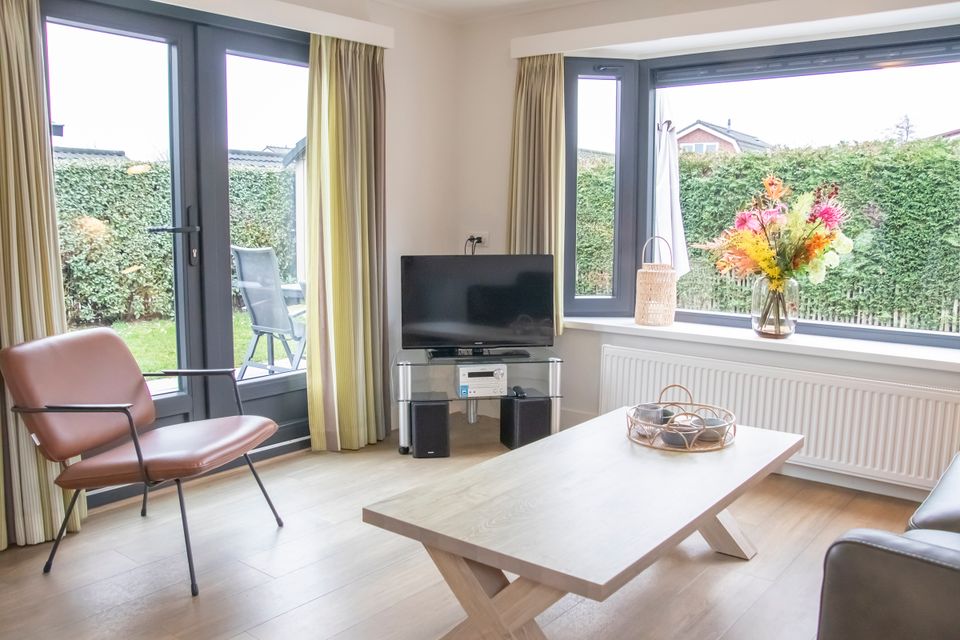 Woonkamer chalet met openslaande deuren naar de tuin.