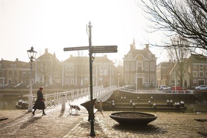 Vrouw loopt met hond langs de grachten van Harlingen