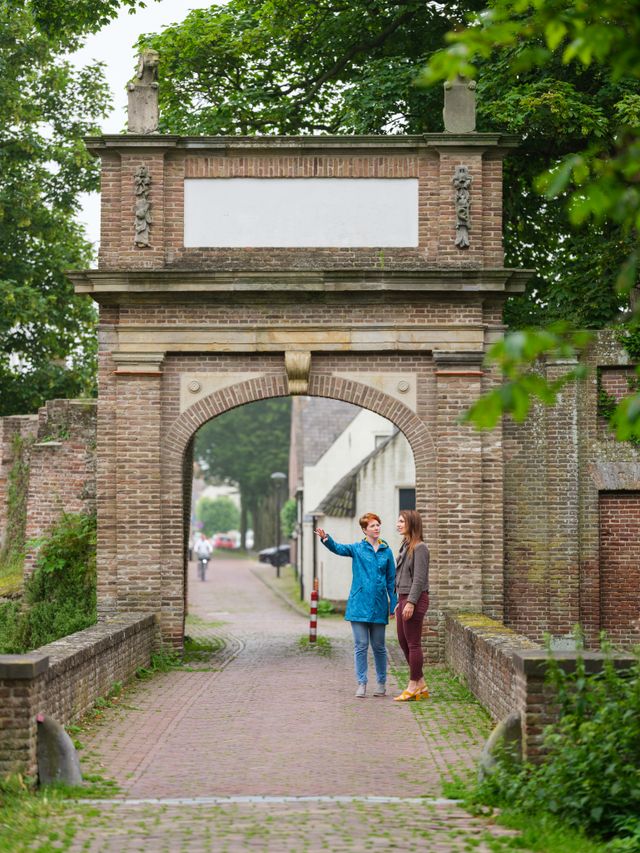 Twee vrouwen staan voor de oude hofpoort van Kasteel Batenstein