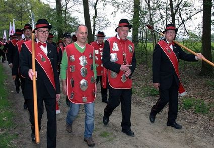 optocht van gildeleden in traditionele kleding met rode sjerpen