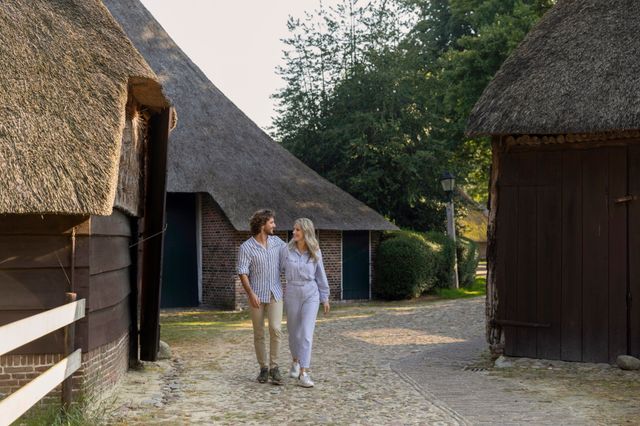 Een stel wandelt tussen de boerderijen door in Orvelte.