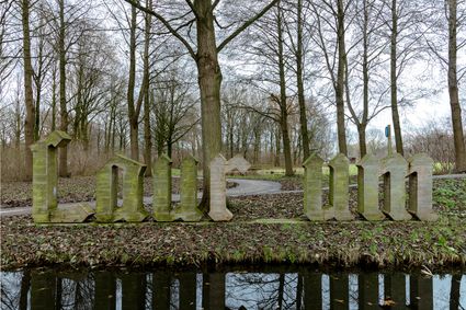 Een bijzonder kunstwerk in het Woerdense Brediusbos, waar de monumentale houten letters Laurium tussen de kale winterbomen opduiken. Met een weerspiegeling in het stille water en een tapijt van bladeren rondom, vormt het kunstwerk een sfeervolle samensmelting van natuur, historie en creativiteit.