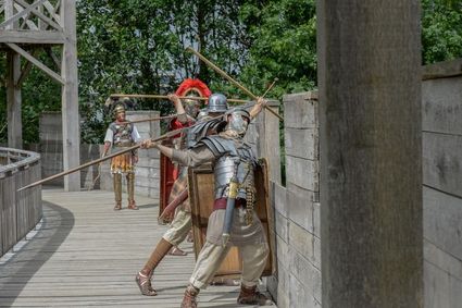 Romeinse soldaten in harnas werpen speren vanaf een houten vestingmuur tijdens een historische reenactment in Archeon, een openluchtmuseum in het Groene Hart.