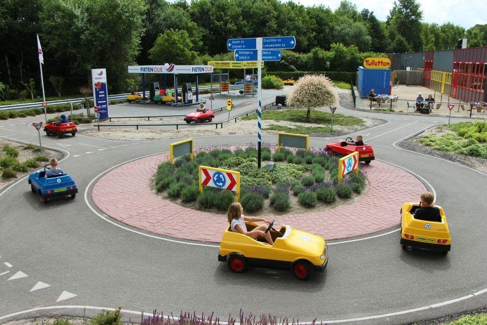 Kinderen rijden in autootjes over de rotonde in het verkeerspark van Duinen Zathe.