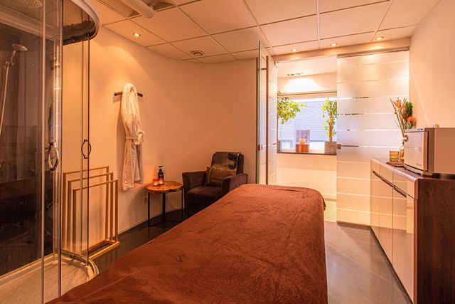 Massageruimte met massage tafel met oranje handdoek