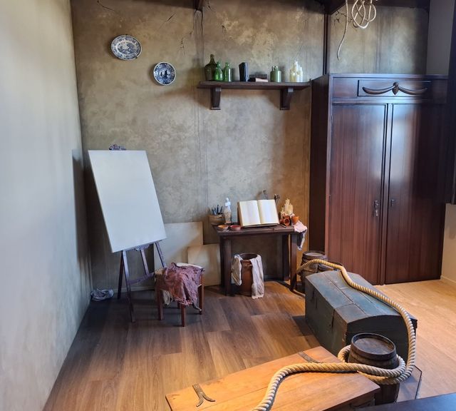 Interieur van de Jan Steen Experience bij VVV Warmond, met attributen uit de 17e eeuw zoals een klassieke kast en kist.