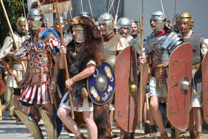 Diverse Romeinse soldaten met helmen en wapens marcheren voorbij.