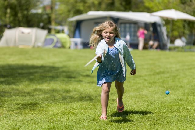 Ein Mädchen spielt Tennis auf einem Rasenplatz auf dem Campingplatz.