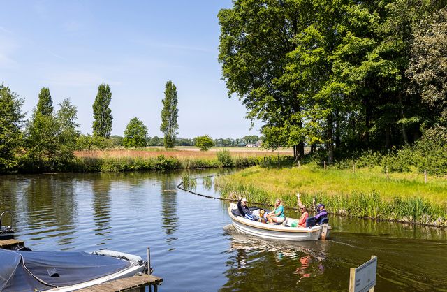 Een groep mensen vaart zwaaiend weg in een sloep bij de Wyldemerk in Friesland.