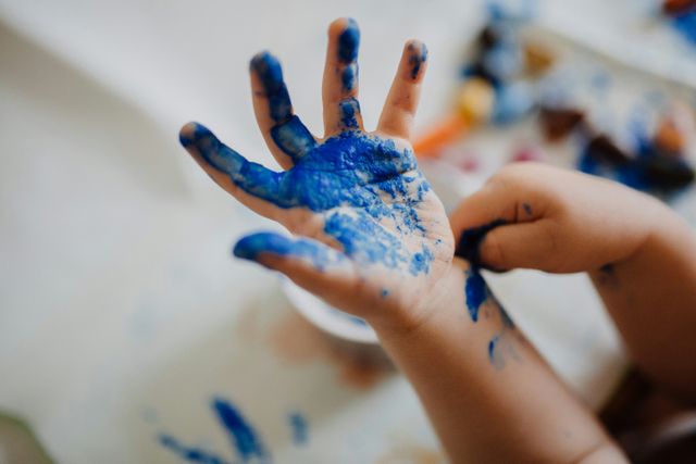 kinderhandje vol blauwe verf