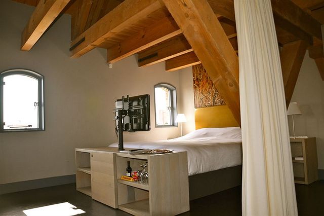 Ein Hotelzimmer mit Balken, in dem ein Doppelbett steht.