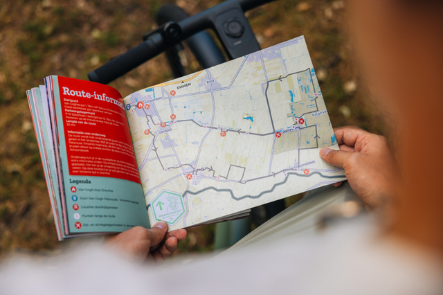 Ein Mann betrachtet die Routenseite im Fahrradroutenheft „Mit dem Fahrrad mit Van Gogh“.