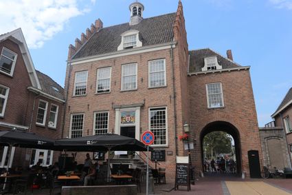 Het Oude Stadhuis in Montfoort, een monumentaal bakstenen gebouw uit de Middeleeuwen met trapgevel, stadscafé-terras en de historische IJsselpoort aan de rechterzijde.