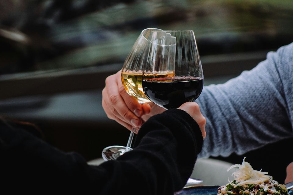 proosten met een glas rode en een glas wiite wijn