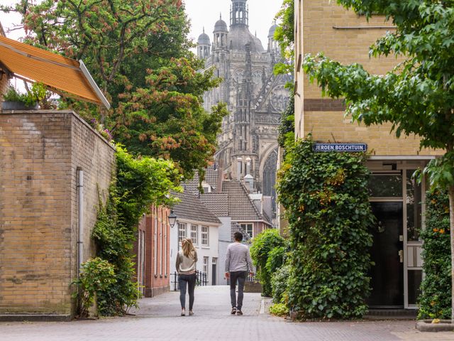 Twee wandelaars in 's-Hertogenbosch met de kerk op de achtergrond