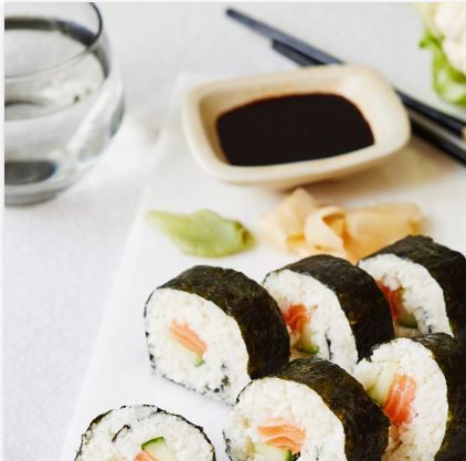 Japans restaurant Sushi Mfort in Montfoort, Groene Hart, close-up van sushirollen met zalm en rijst op een lichte ondergrond, geserveerd met sojasaus en eetstokjes als beeld van verse Aziatische gerechten.