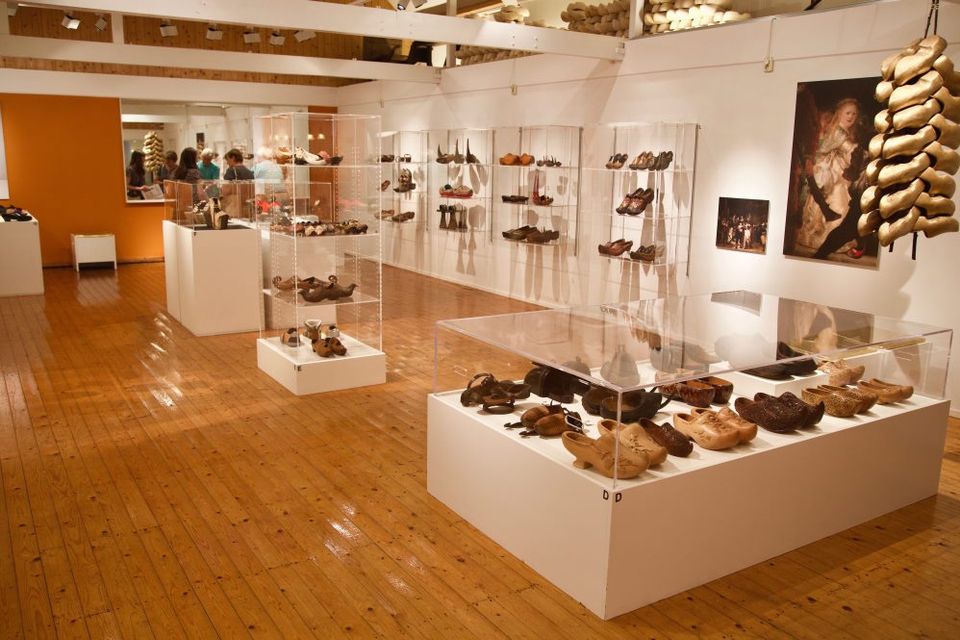 Verschiedene Holzschuhe werden in einem Raum mit Glasvitrinen im Museum ausgestellt.