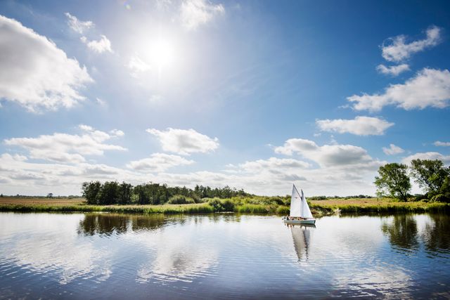 Vergezicht over een meer in Friesland met hierop een kleine zeilboot