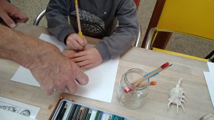 Hans Post helpt een kind met het natekenen van een schelp