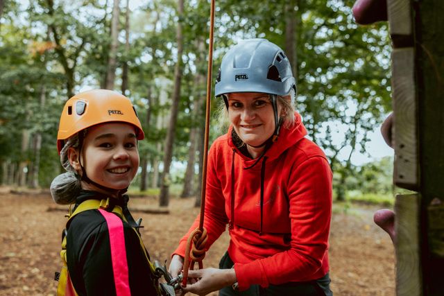 Moeder helpt haar zoon om de ziplijn van het Klim- en avonturenbos vast te houden