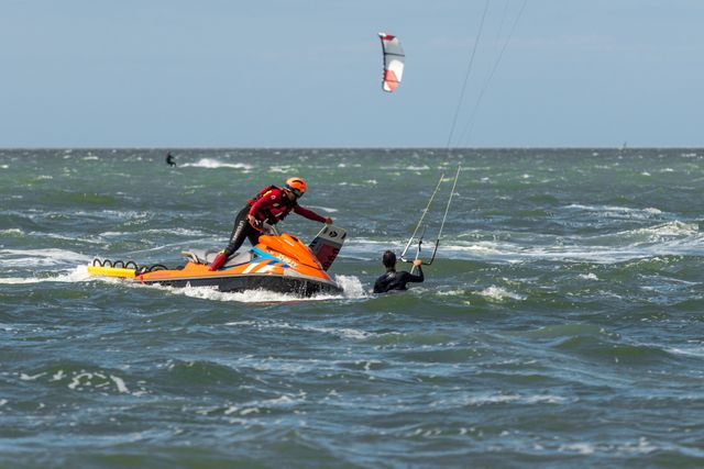 Reddingsbrigade op jetsky helpt surfer op het water