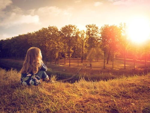 Een meisje zit boven op een aarde wal van Fort de Roovere, en kijkt uit over het fort en de Mozesbrug.
