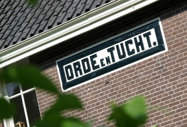 De woorden 'Orde en tucht' op de gevel van een woning in de voormalige dwangkolonie Veenhuizen.