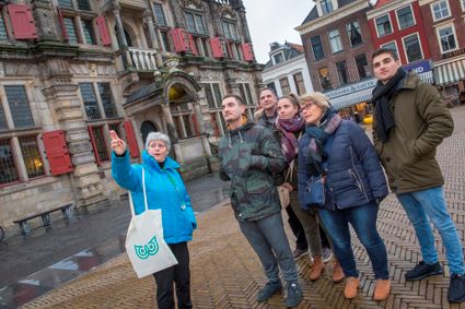 Groep mensen die uitleg krijgt tijdens een Vermeer wandeling naast het Stadhuis in het Centrum van Delft