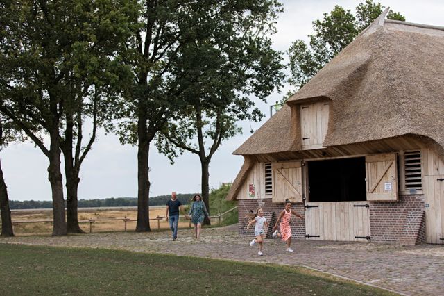 Die Kinder rennen vor den Eltern her zu einem Schafstall in Drenthe.