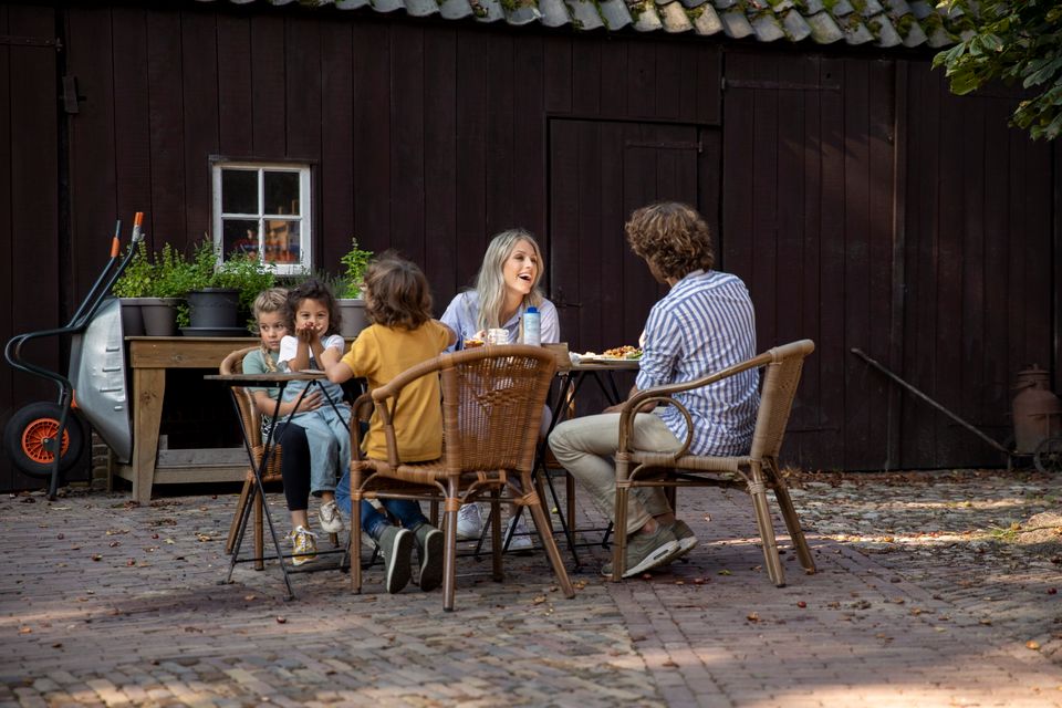 Een gezin met drie kinderen zit een hapje te eten op het terras.