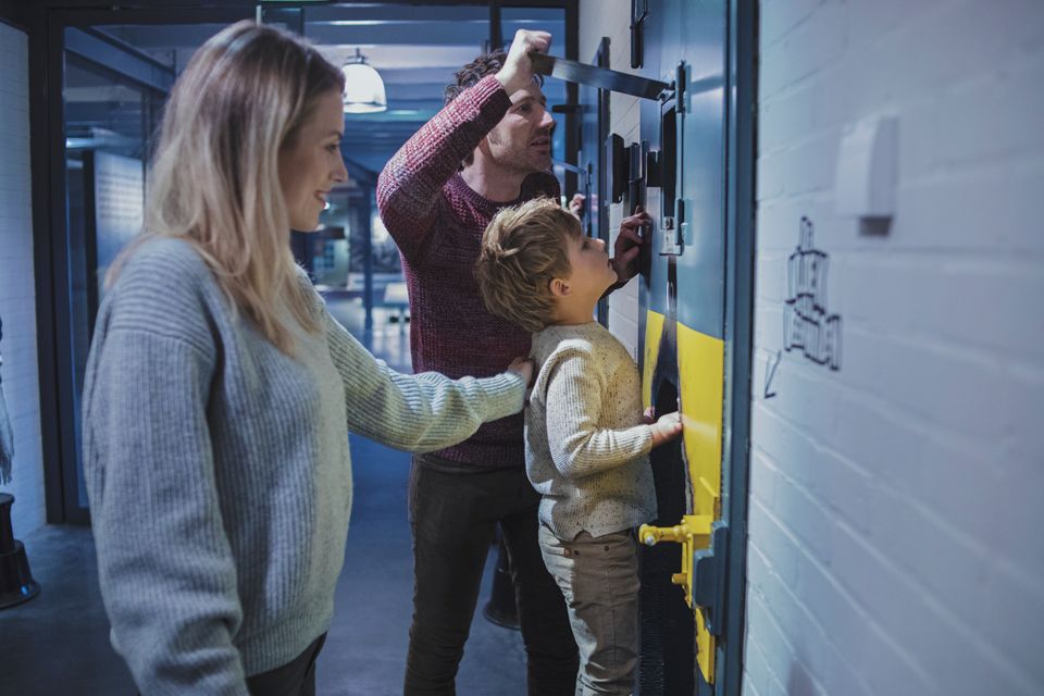 Een jongetje kijkt met zijn ouders door het luik van een celdeur