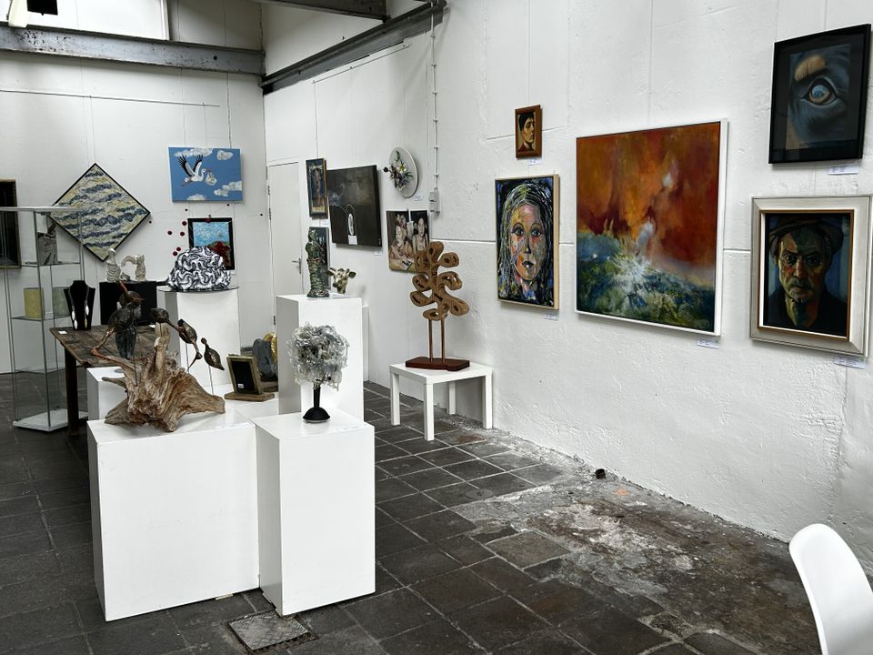 Kunstgalerie tijdens Atelierroute Woerden in Woerden, Groene Hart, expositieruimte met schilderijen, portretten en abstracte kunst aan witte muren en verschillende beelden en sculpturen op sokkels.