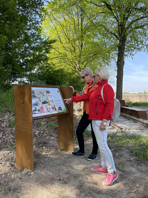 Twee dames kijken op een informatiebord voor de wandeling Ommetje Coupure in Kruisland.