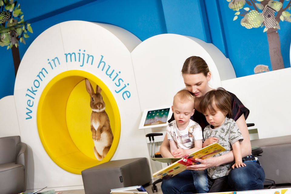 Vrouw leest samen met twee kinderen een kinderboek bij de kinderafdeling van de Bibliotheek in het StadsForum in Zoetermeer.