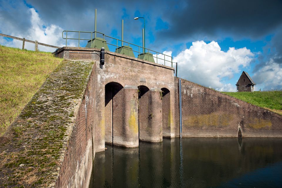 Een grote bakstenen sluis met groene pijlers.