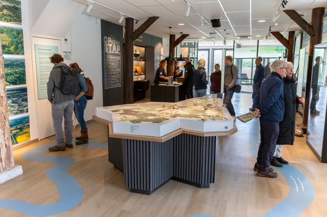 Een natuurbezoekerscentrum waar mensen informatie lezen over Nationaal Park Drentsche Aa.