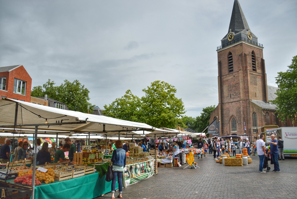 Gezellige streekmarkt in het centrum van Woerden met marktkramen en de Petruskerk op de achtergrond.