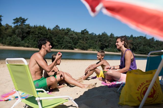 Een gezin geniet van een zomers dagje aan zwemplas Kibbelkoele, midden in de Drentse natuur.