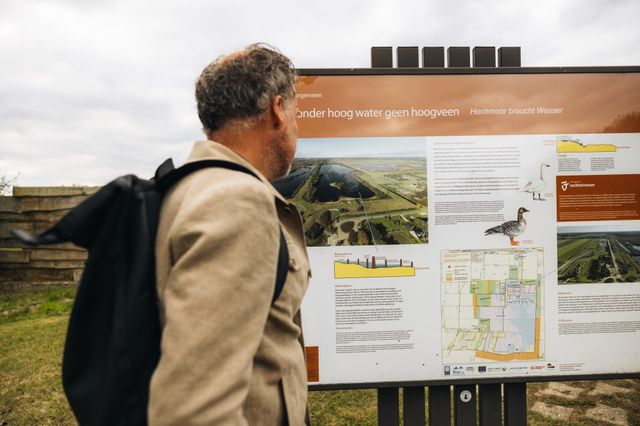Een man kijkt op een informatiebord langs een fietsroute door het natuurgebied Bargerveen.