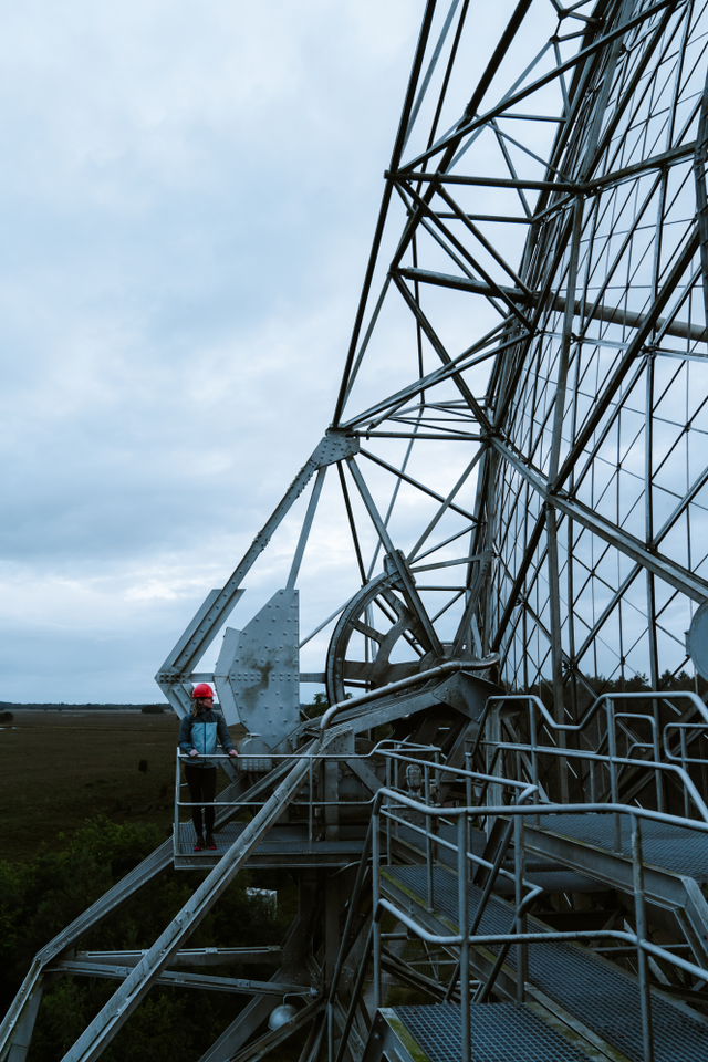 Een man staat op grote hoogte bij de radiotelescoop van Dwingeloo.